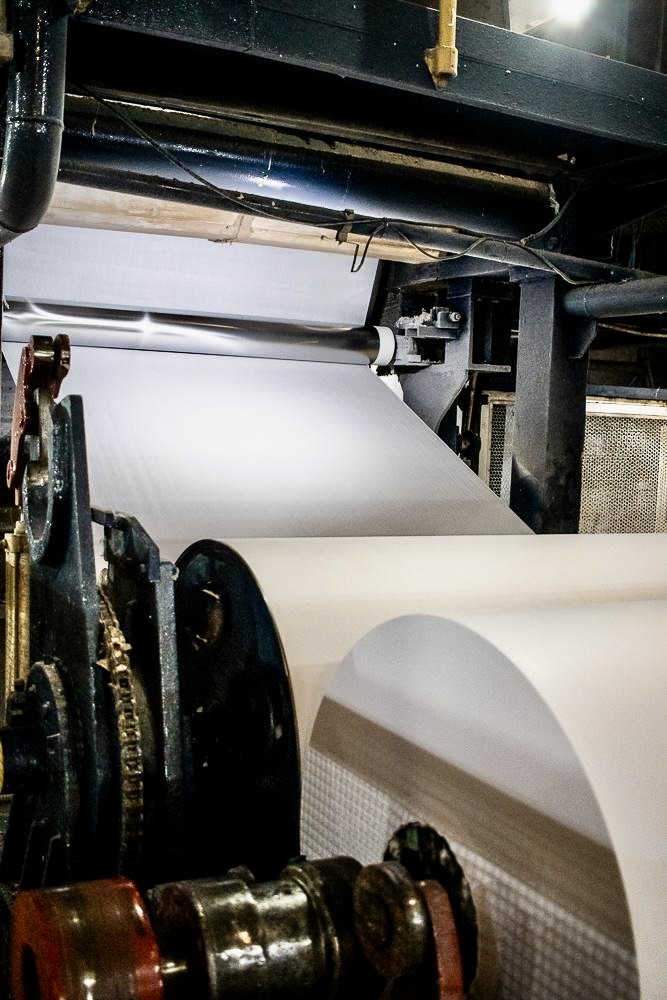 Folha de papel branco saindo da máquina de papel da Taquari Papéis